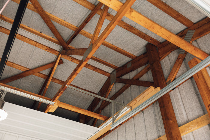 Exposed wood post-frame trusses and purlins under a metal roof liner