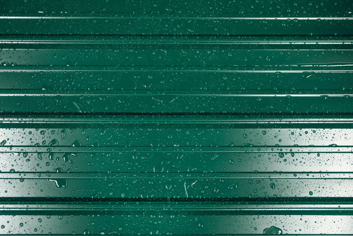 Close-up of green standing seam metal roof panels with water droplets